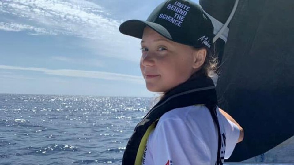 Greta Thunberg pose sur un bateau en mer.