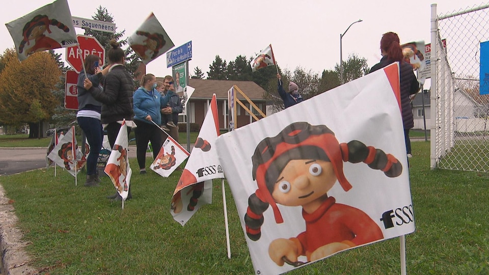 Des éducatrices et des parents manifestent en bordure d'une rue.