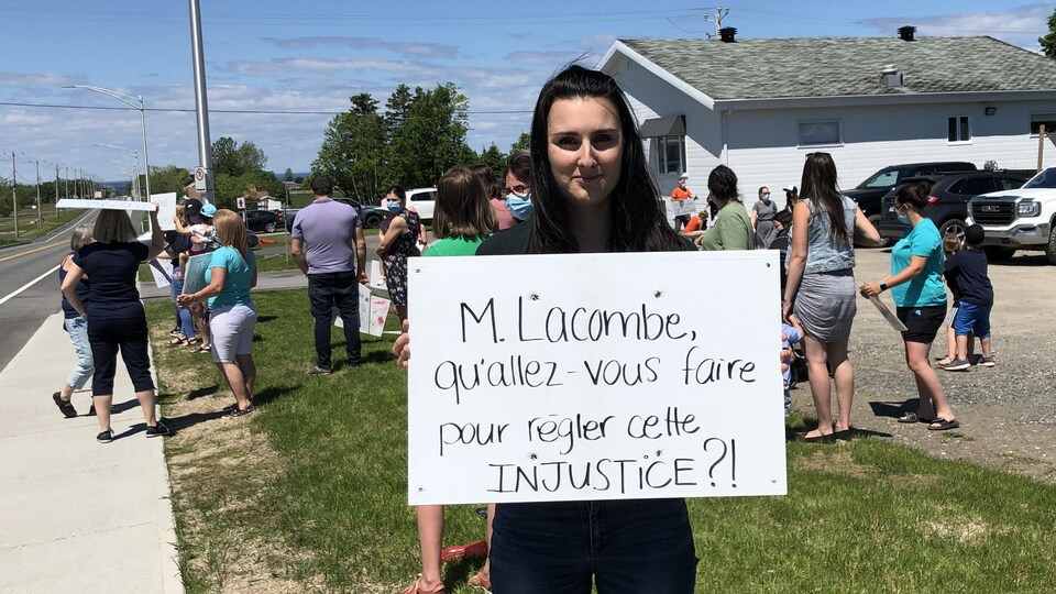 La directrice adjointe et copropriétaire des Minis explorateurs, Élisabeh Fillion brandit une pancarte où on peut lire : «M. Lacombre qu'allez-vous faire pour régler cette injustice? »