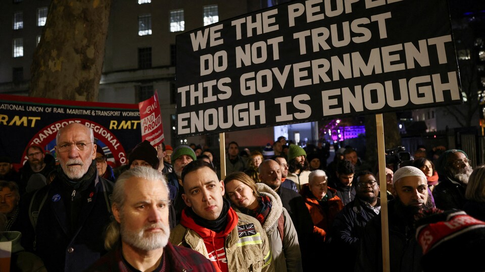 Des manifestants près du 10, Downing Street, la nuit, tenant des pancartes.