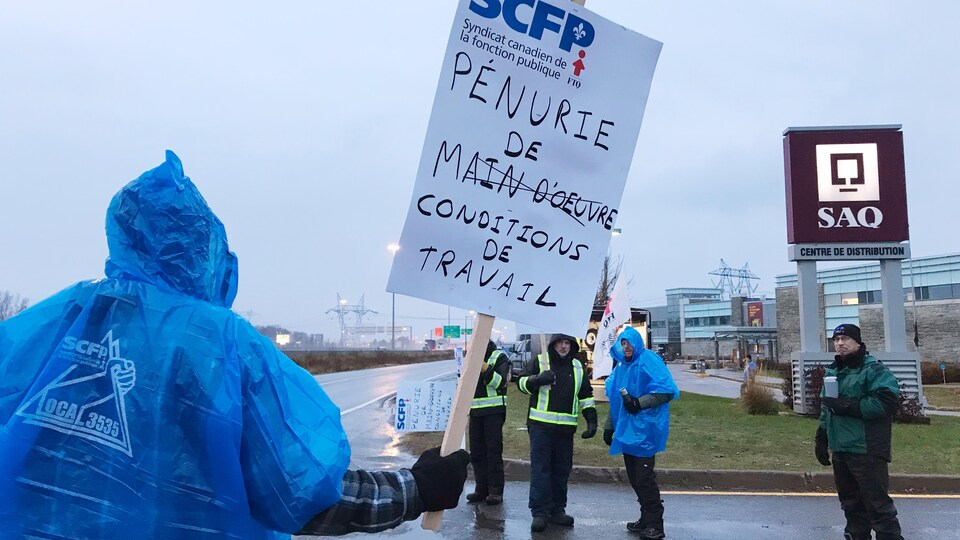 Un gréviste tient une pancarte où il est inscrit : « Pénurie de conditions de travail ».
