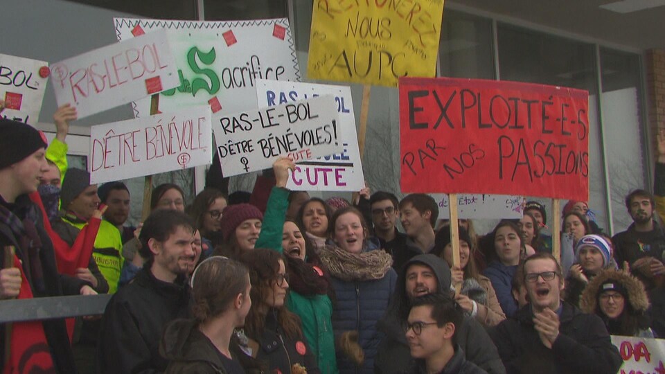 Des étudiants tiennent des pancartes.