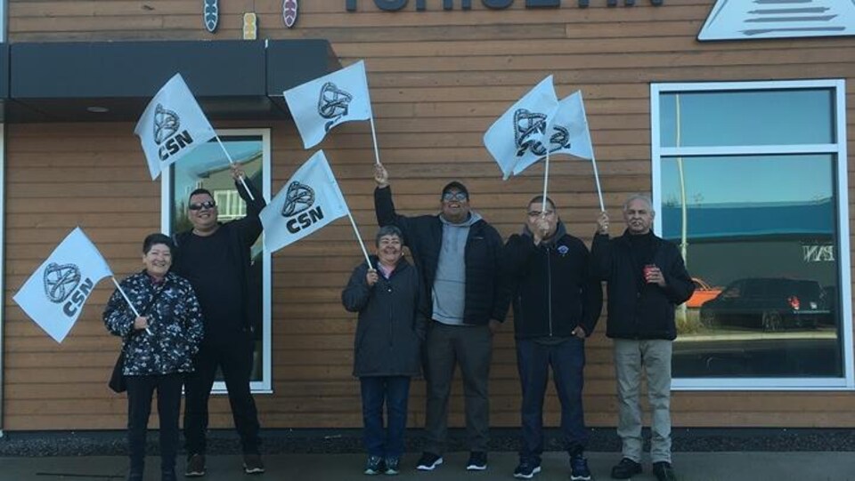 Des employés avec des drapeaux de la CSN devant les bureaux de Tshiuetin.