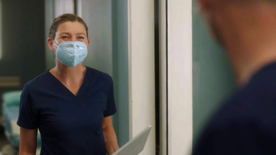 Meredith Grey porte une tenue de médecin et un masque.