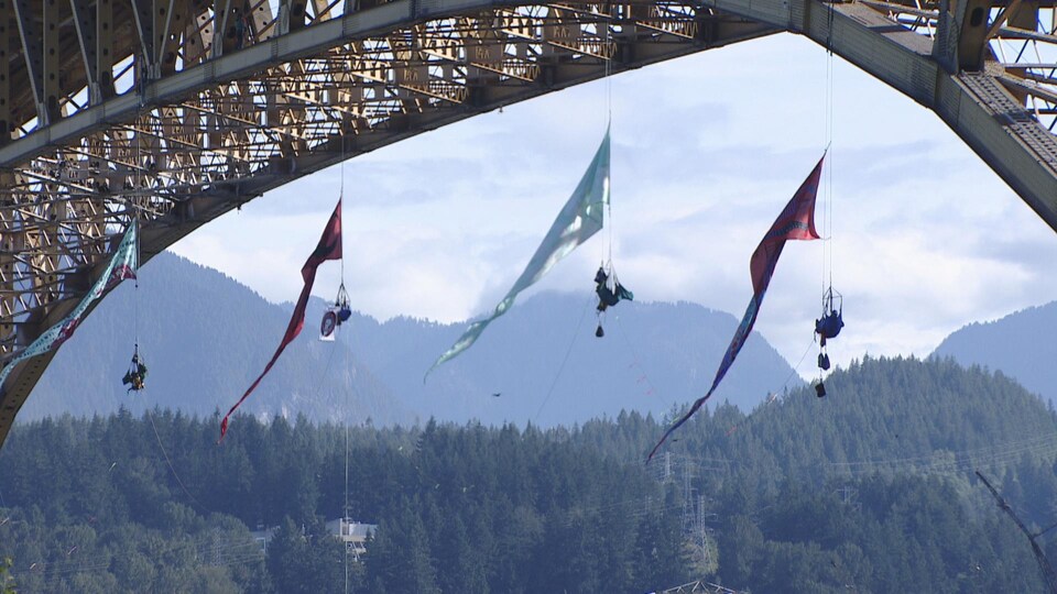 Quatre grimpeurs suspendus à un pont.