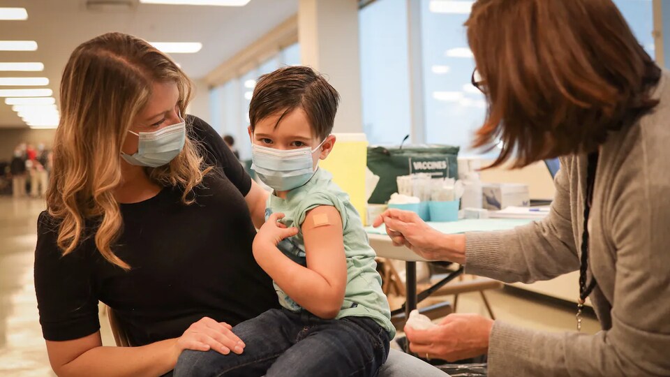 Un enfant assis sur les jambes de sa maman vient de se faire vacciner contre la grippe.