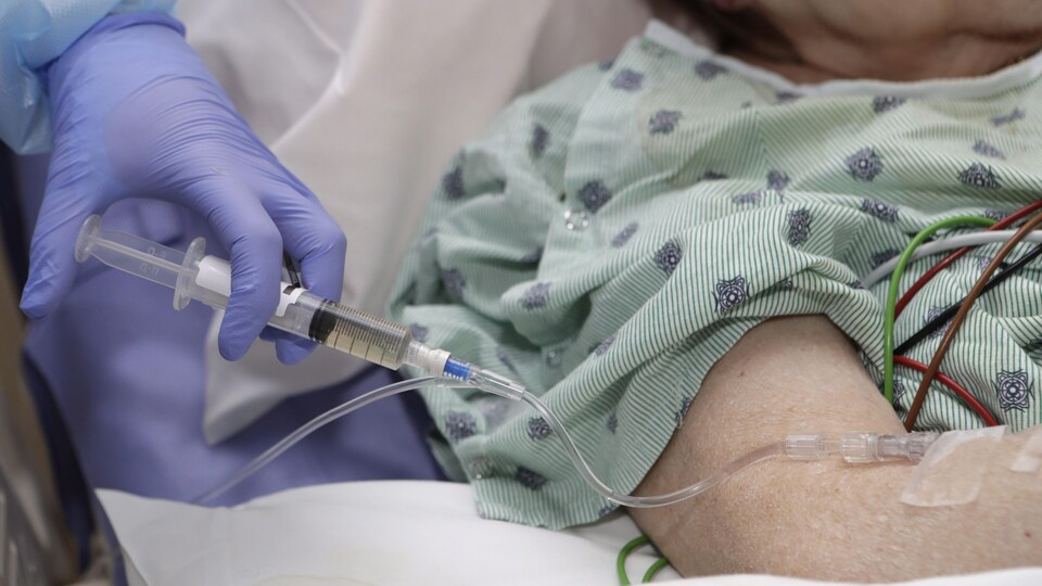 Une infirmière injecte un médicament par intraveineuse.