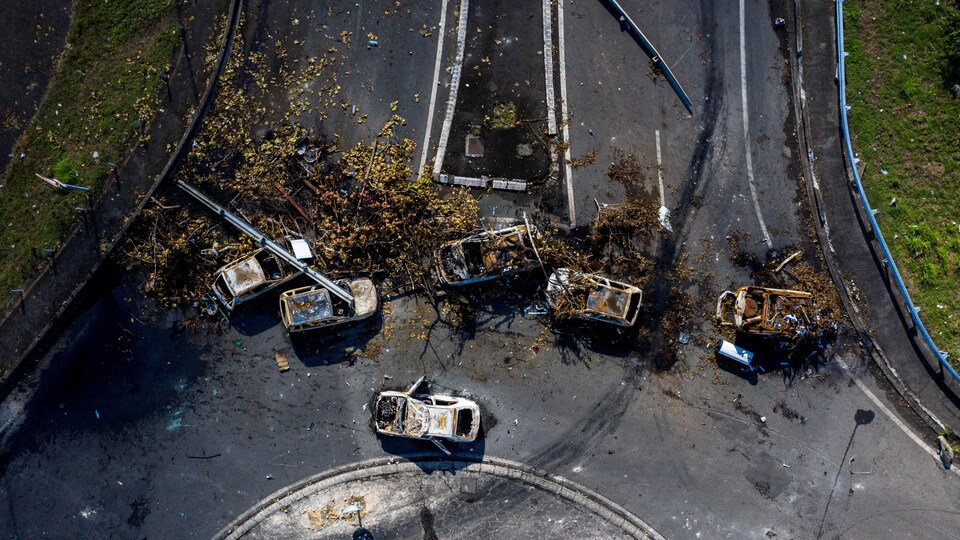 Vue aérienne d'une route coupée avec des voitures brûlées.