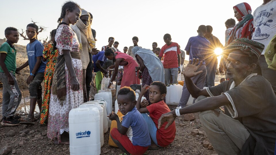 Des réfugiés qui se servent de l'eau dans des bidons de l'UNICEF.