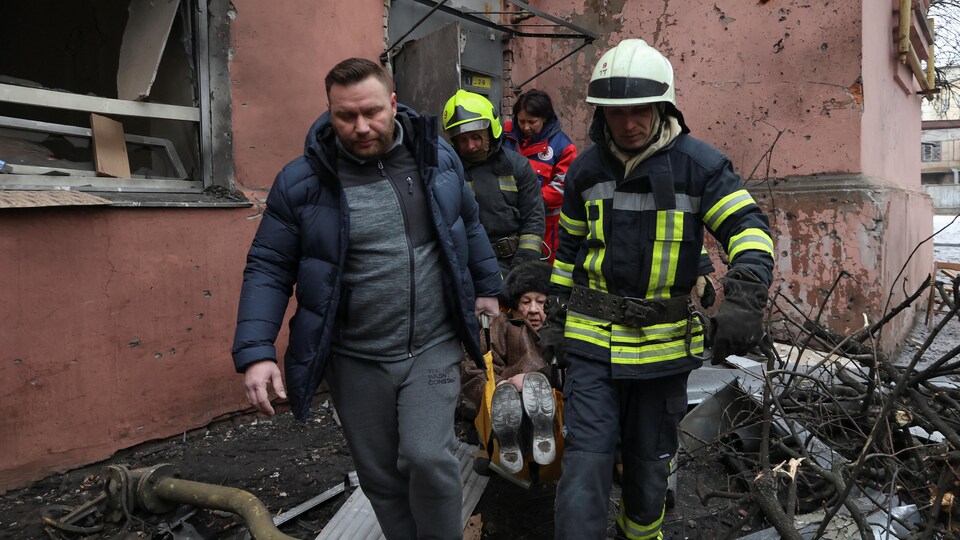 Des sauveteurs transportent sur un brancard une femme blessée à la suite d'un tir de missile russe sur un immeuble résidentiel, à Kharkiv, en Ukraine.