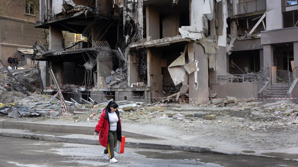 A woman walks in front of a building destroyed by strikes in a kyiv district. 