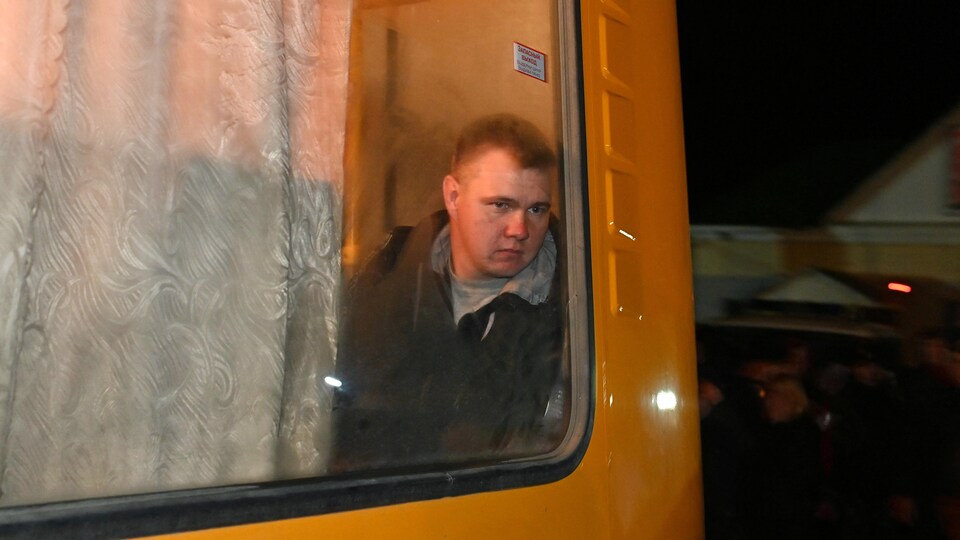 Un homme au regard triste assis dans un autobus jaune.