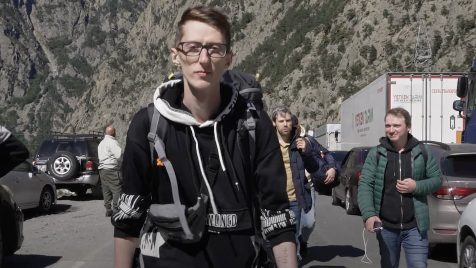 Un groupe de jeunes hommes marchent sur une route en Géorgie.