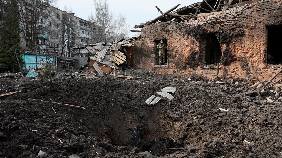 Un militaire ukrainien utilise son téléphone près d'un cratère à la suite d'un bombardement meurtrier dans un quartier résidentiel de Kostiantynivka, en Ukraine, le 2 avril 2023.
