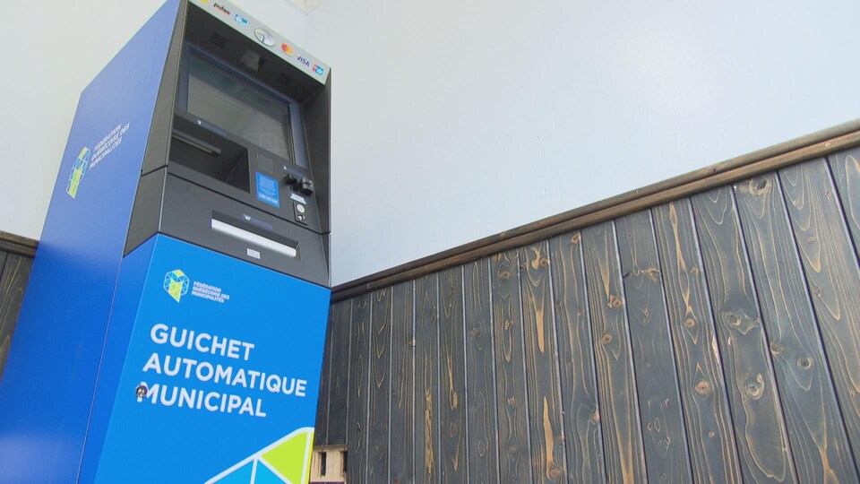 Un guichet automatique municipal installé dans une petite pièce.