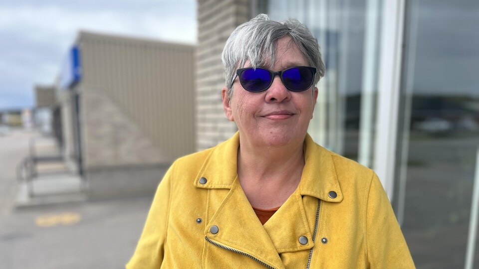 La coordonnatrice du Centre d'aide et de lutte contre les agressions à caractère sexuel (CALACS) de Baie-Comeau, Guilaine Levesque, souriant à l'extérieur avec des lunettes de soleil.