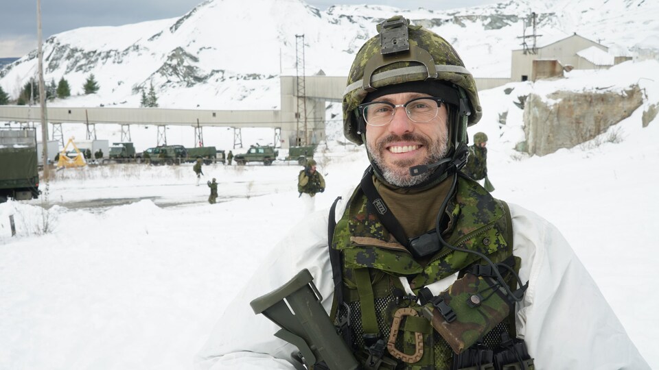 Un militaire se tient debout et sourit.