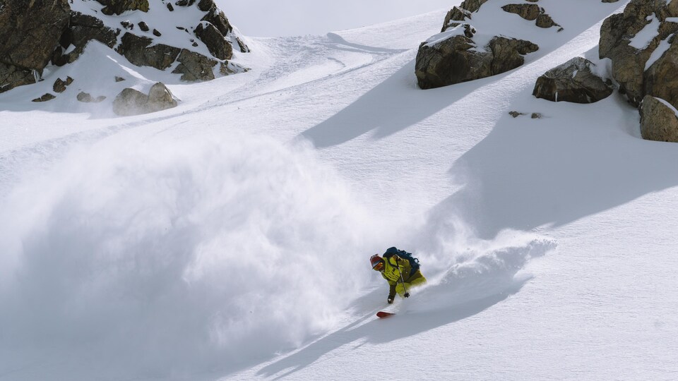 Un homme est en train de descendre une montagne à skis, en hors-piste.