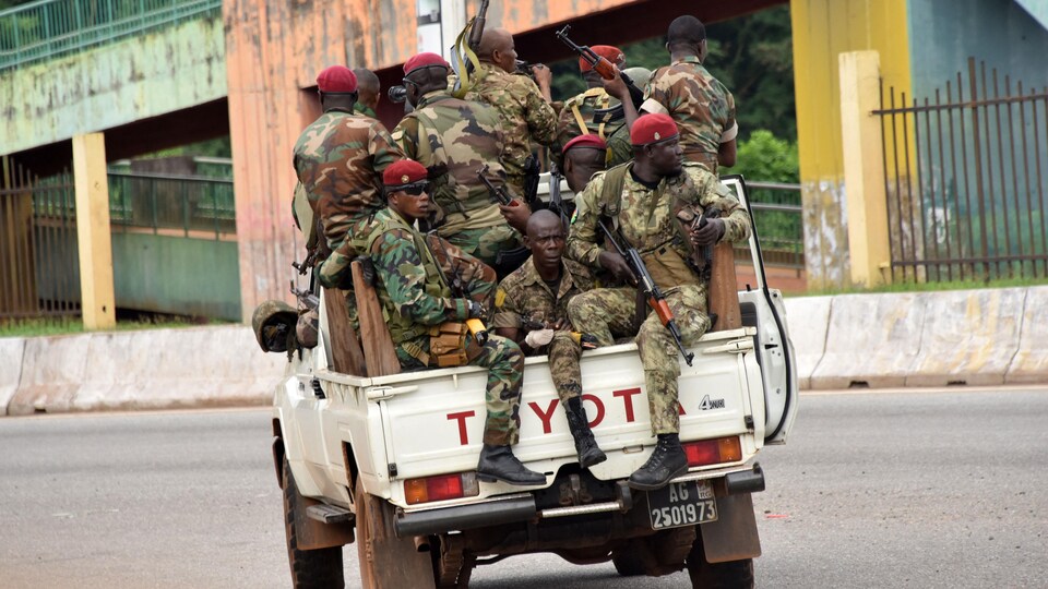 Des militaires guinéens armés dans la boîte d'une camionnette.