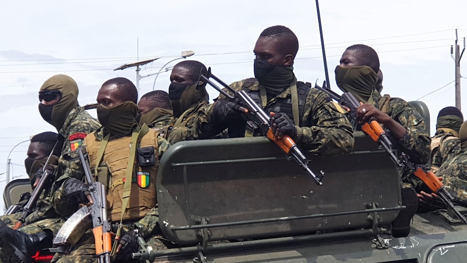 Plusieurs militaires armés dans un véhicule militaire. 