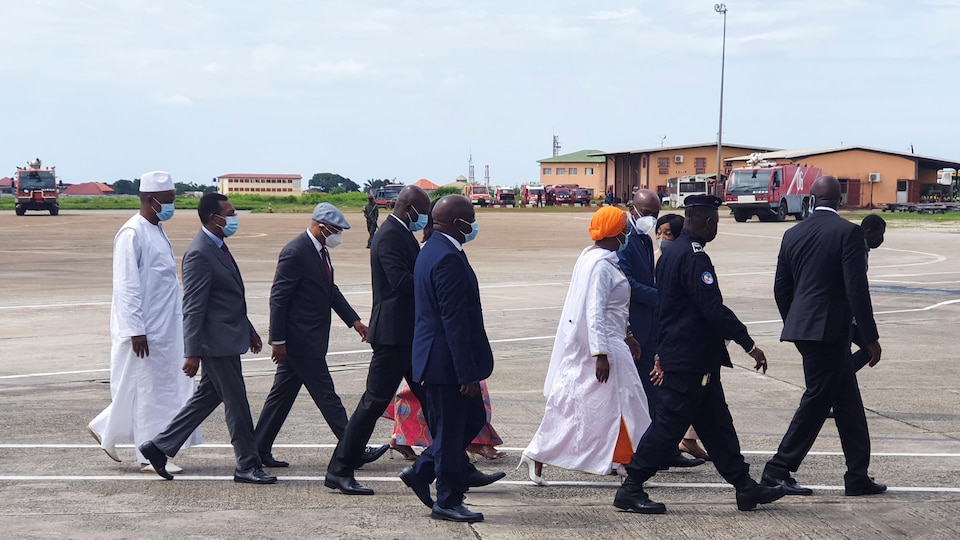 Plusieurs personnes marchent sur le tarmac d'un aéroport.