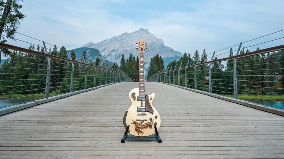 Une guitare affichée sur un pont avec la nature en arrière-plan.