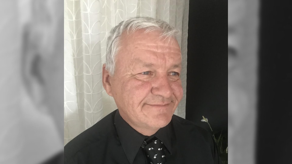 Un homme portant une chemise et une cravate regarde au loin, souriant.