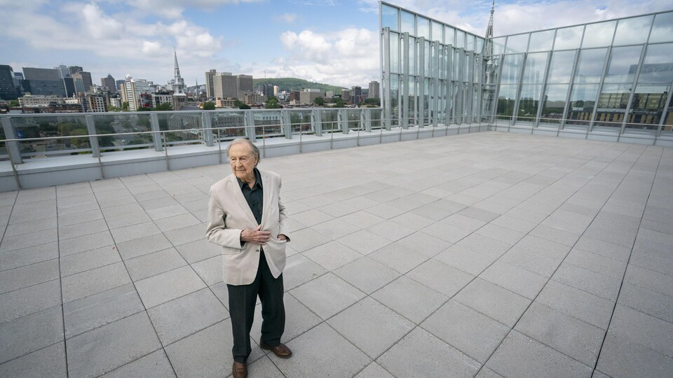 Guy Rocher debout sur la terrasse de la Nouvelle Maison de Radio-Canada.