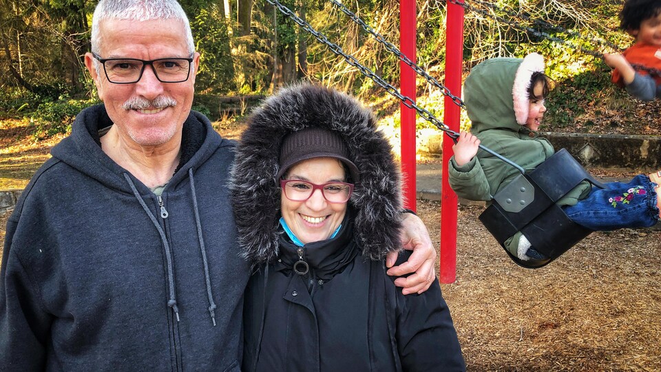 Un couple pose devant une structure de jeux pour enfants.
