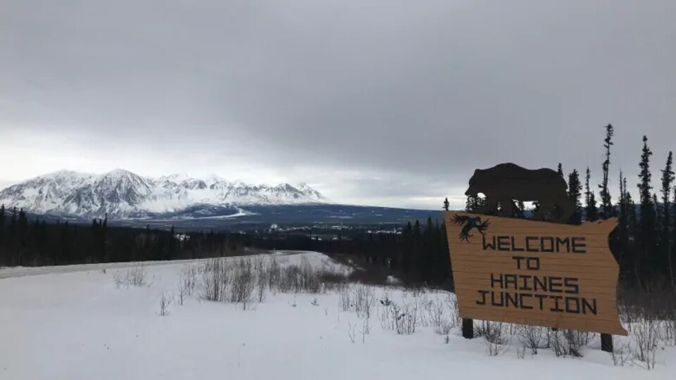 Un panneau indiquant l'arrivée à Haines Junction au bord d'une route.