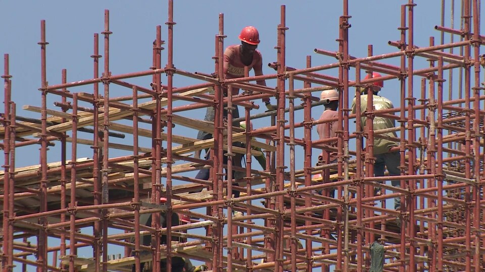 En Haïti, des hommes s'affairent sur les échafaudages d'un chantier de construction.
