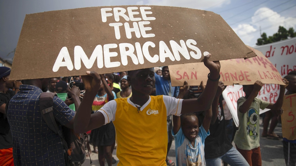 Un manifestant brandit une pancarte sur laquelle on peut lire : Libérez les Américains.
