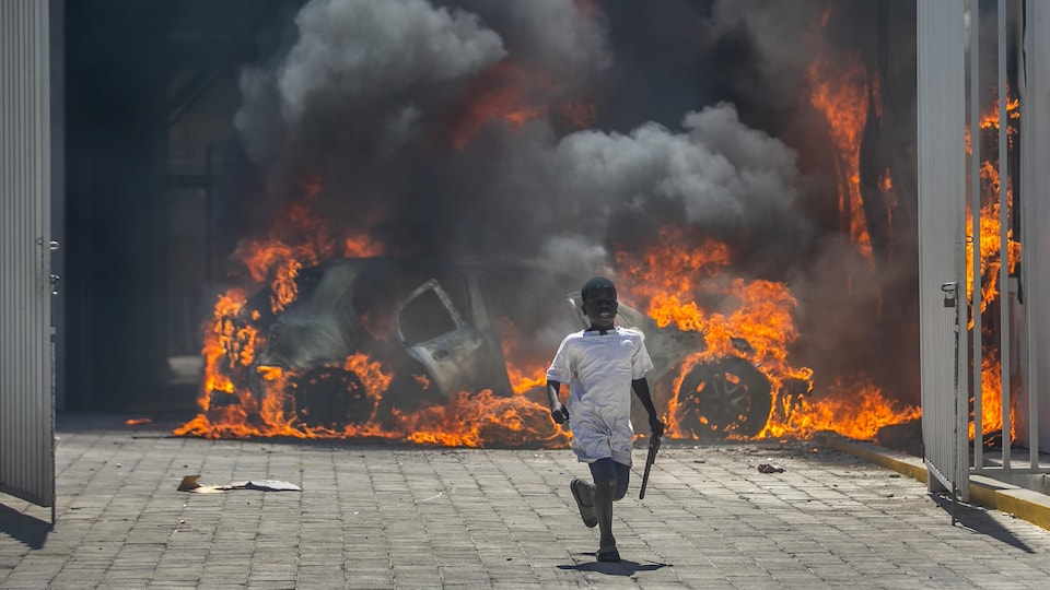 Un enfant court pour s'éloigner d'un véhicule, derrière lui, qui est en flammes.