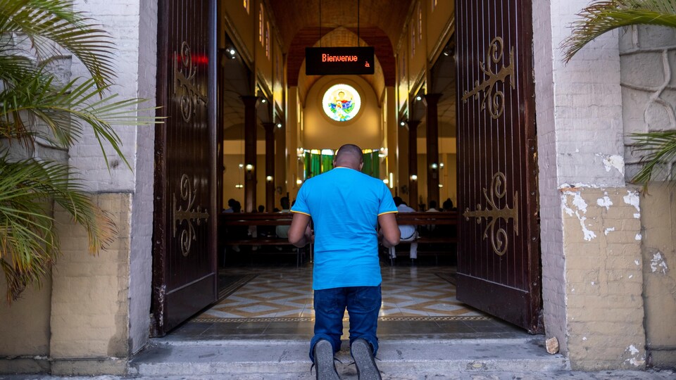 Un homme prie à l'entrée d'une église pendant la messe du dimanche à Port-au-Prince.