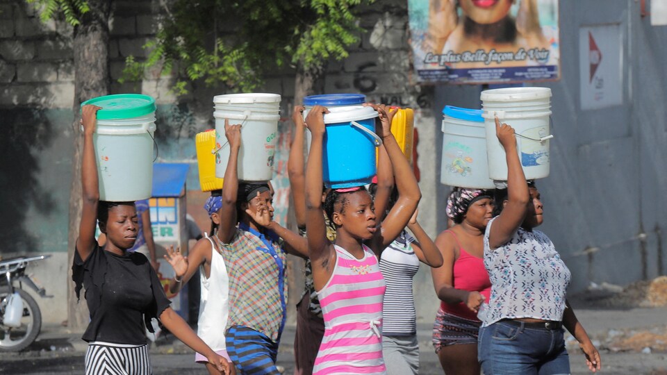 Des femmes transportent des seaux d'eau sur leur tête.