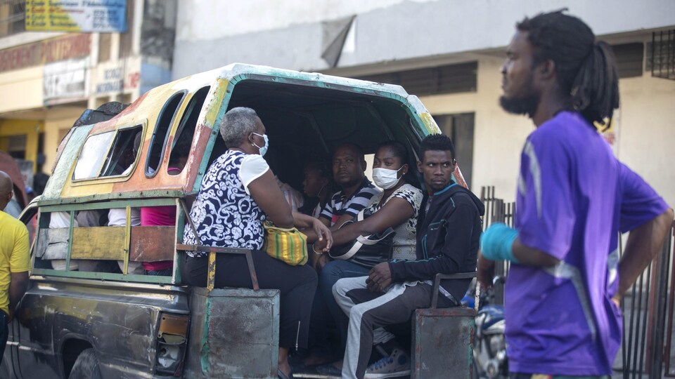 Des passagers dans une camionnette ouverte dans une rue de Port-au-Prince.