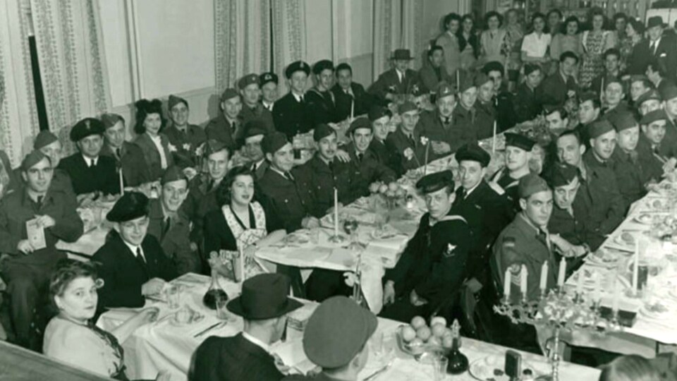 Une cantine pleine à craquer d'hommes en uniforme entourés de femmes dans les années 40