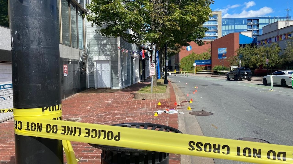 Une banderole de la police bloque l'accès à une section de la rue. Du sang au sol est visible. 