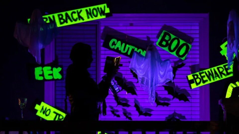 Une personne traverse une salle avec des lumières et des décorations d'Halloween.