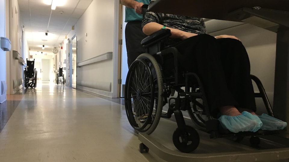 Une femme en chaise roulante dans un couloir.