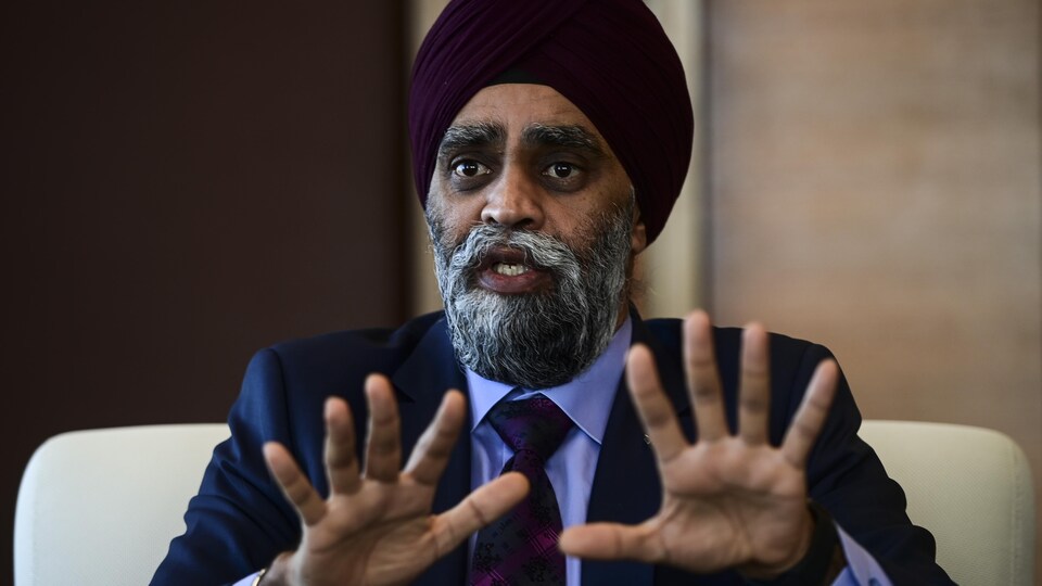 Harjit Sajjan parle et lève les deux mains devant lui.