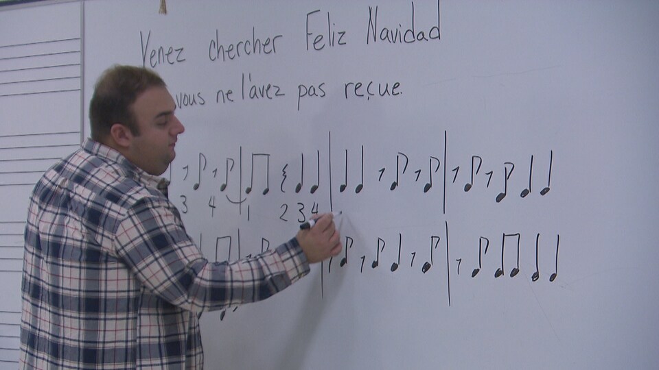 Un homme écrit des notes de musique sur un tableau d'école 