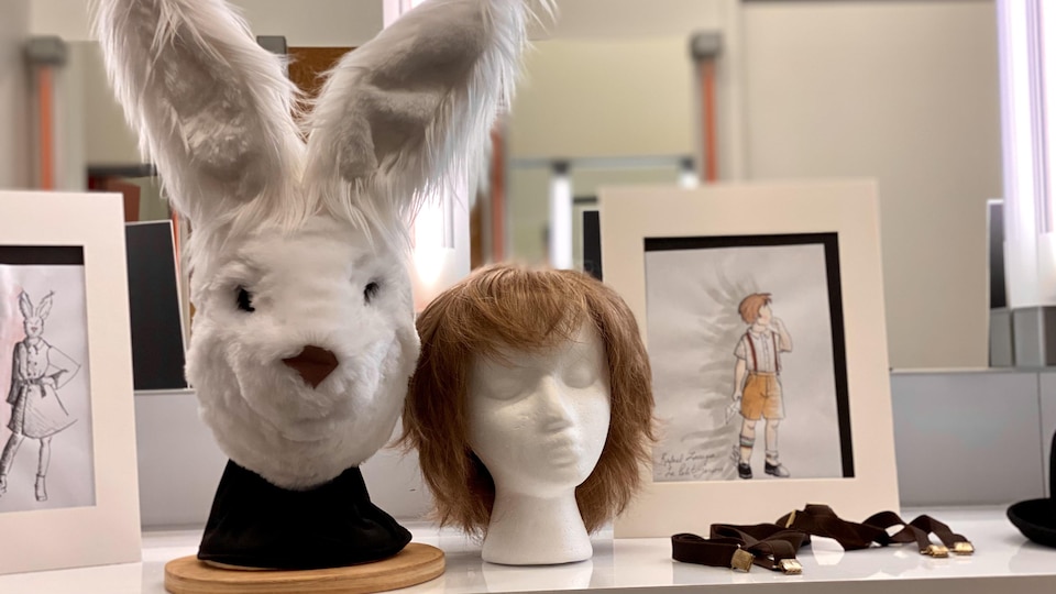 Un masque de lapin et une perruque sont déposés sur des socles. 