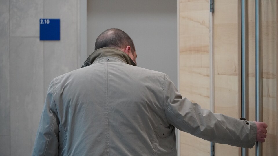 Un homme tient la poignée de la porte d'une salle d'audience au palais de justice de Rimouski.