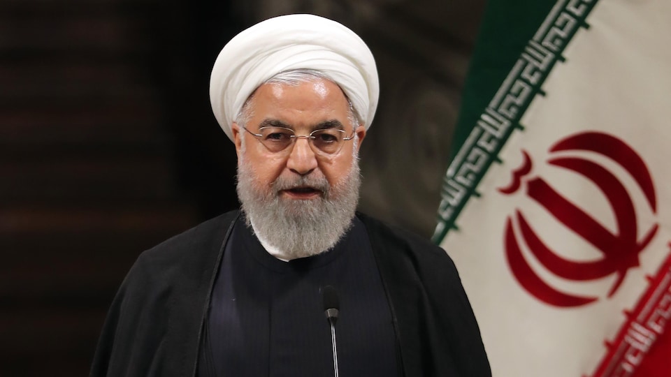 Le président iranien Hassan Rohani parle dans un micro avec un air déterminé. 