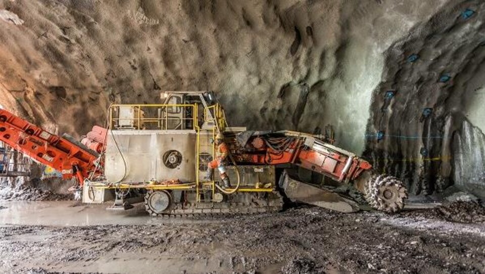 On voit l'excavatrice à l'oeuvre dans une cavité creusée dans le sol.