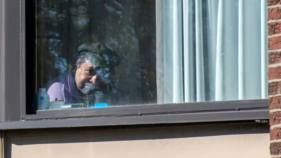 Un résident regarde par la fenêtre au centre de soins Hawthorne Place, à Toronto.