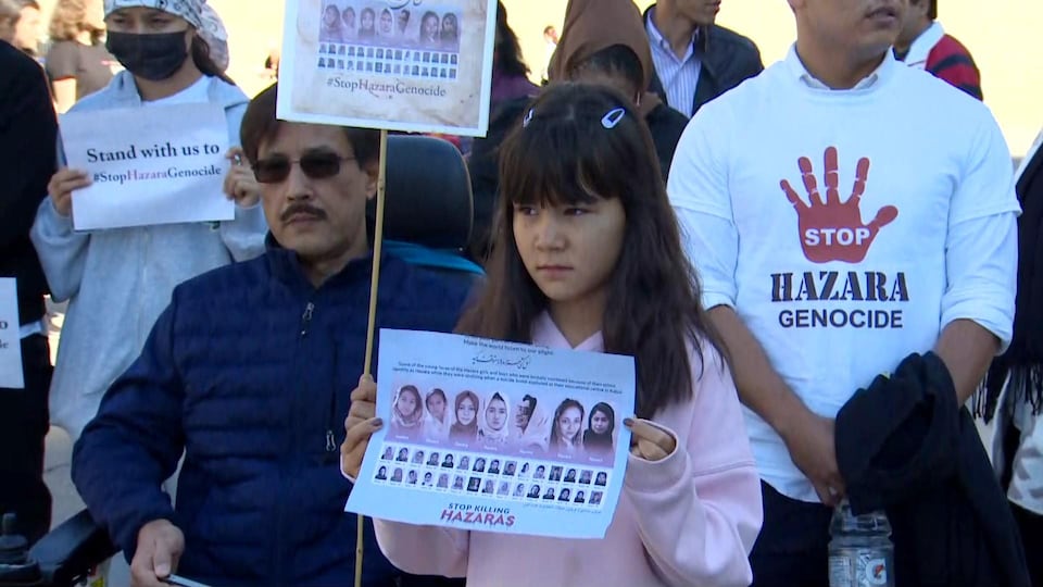 Une jeune fille tient une pancarte avec le visage des filles tuées dans une explosion terroriste en Afghanistan.