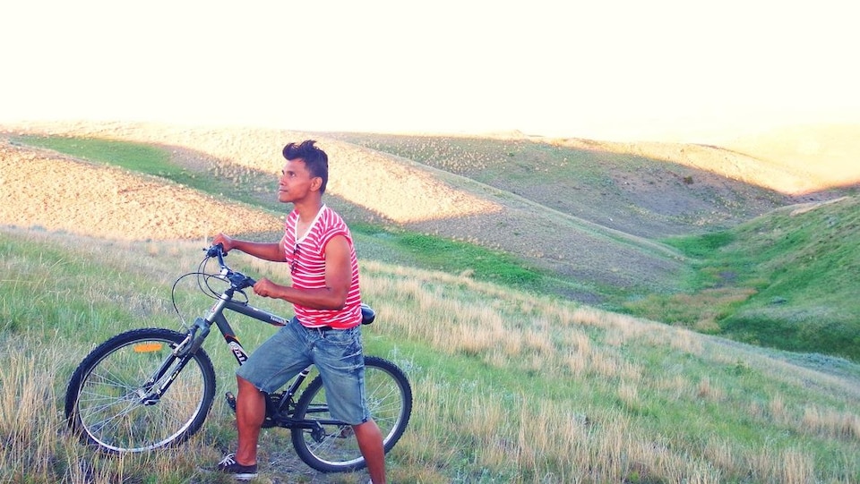 Un jeune homme avec un vélo sur une colline. 