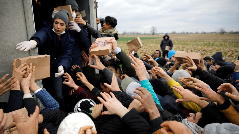 Des membres du Haut-Commissariat des Nations unies pour les réfugiés livrent de la nourriture aux migrants.